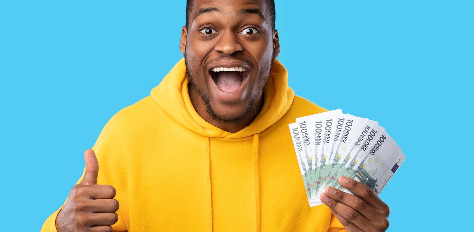 A photo of an excited man holding banknotes in one hand and giving the thumbs up sign with the other