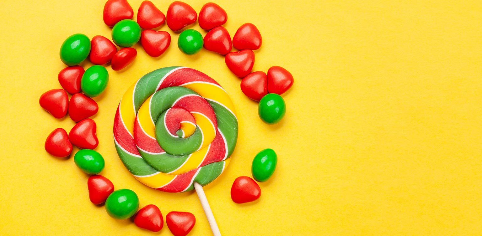A photo of an assortment of red and green candies on a bright yellow background