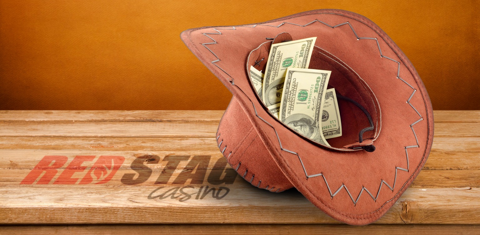 An image of a cowboy hat filled with 100 dollar bills on a white background