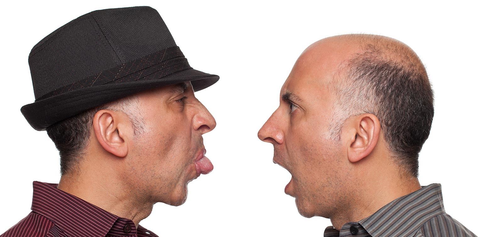 A close-up photo of identical twins fighting against a white background 