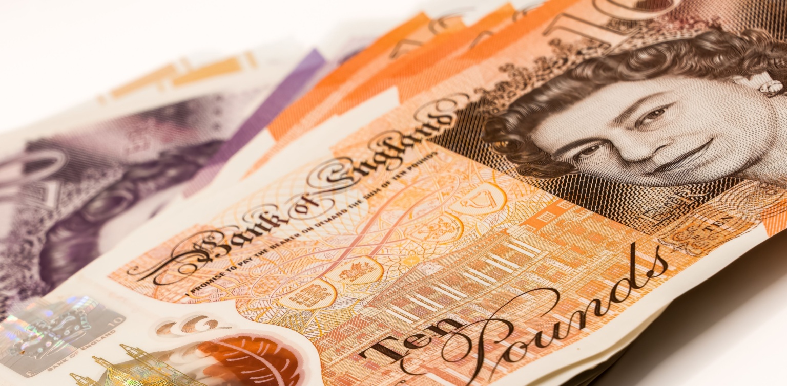 A close-up image of a stack of GPT with a ten Pound note on top, on a white surface