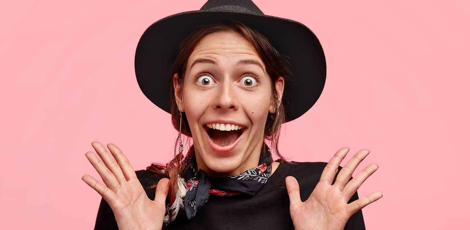 A photo of a surprised and obviously happy cowgirl isolated on a pink background